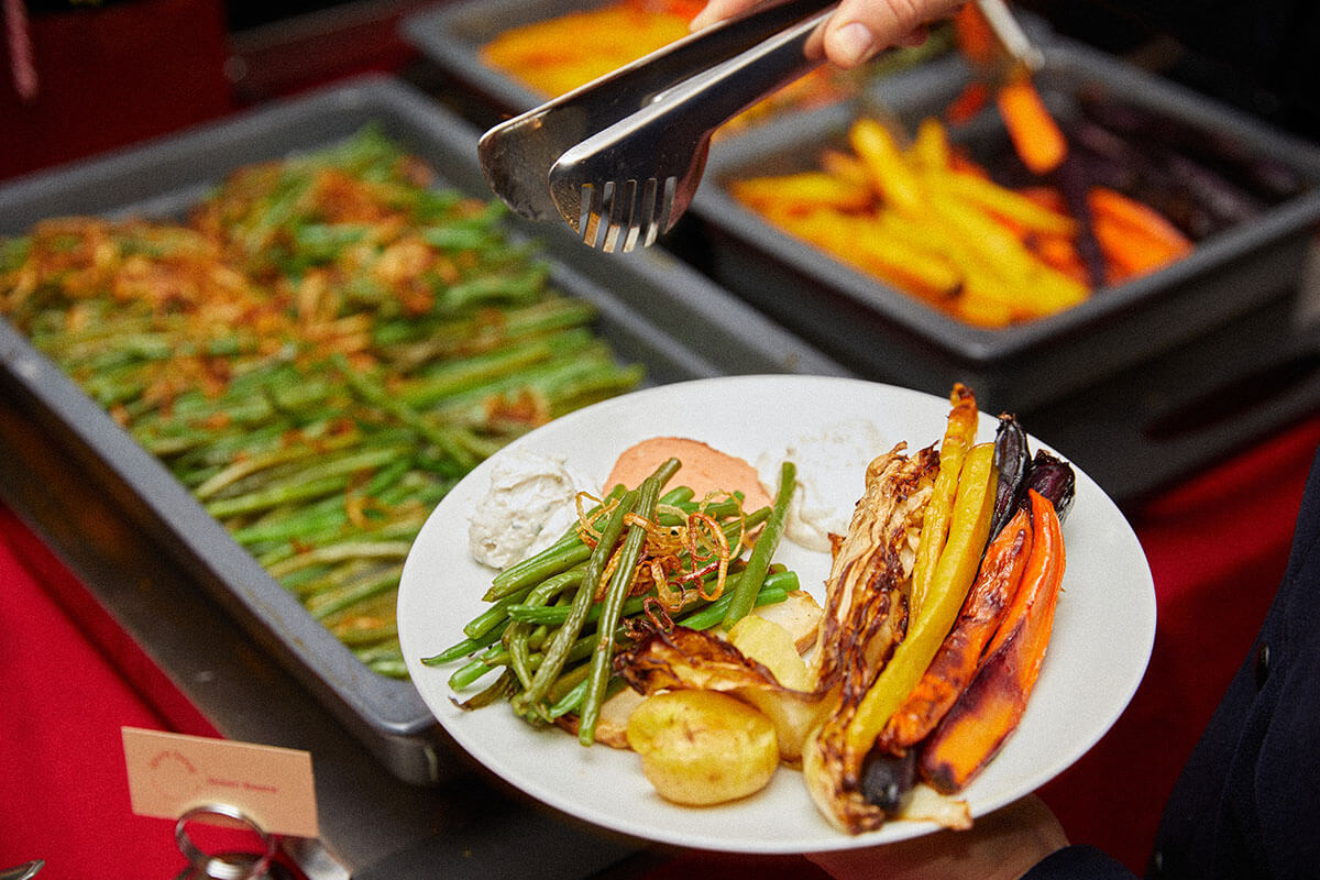 People serving food onto their plate from a buffet