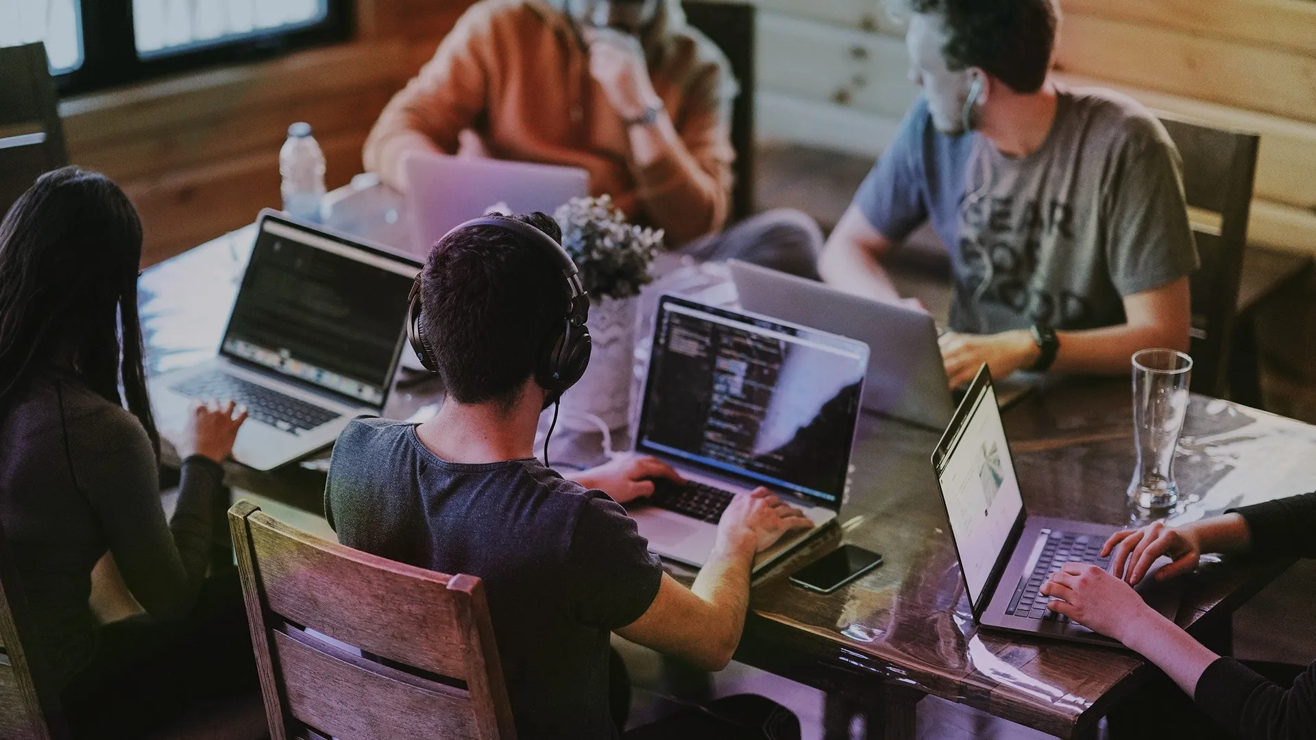 A groupd of people working at a table with laptops