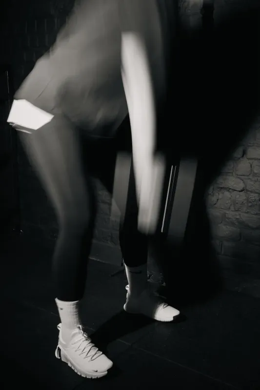 greyscale photo of woman in bralette inside room
