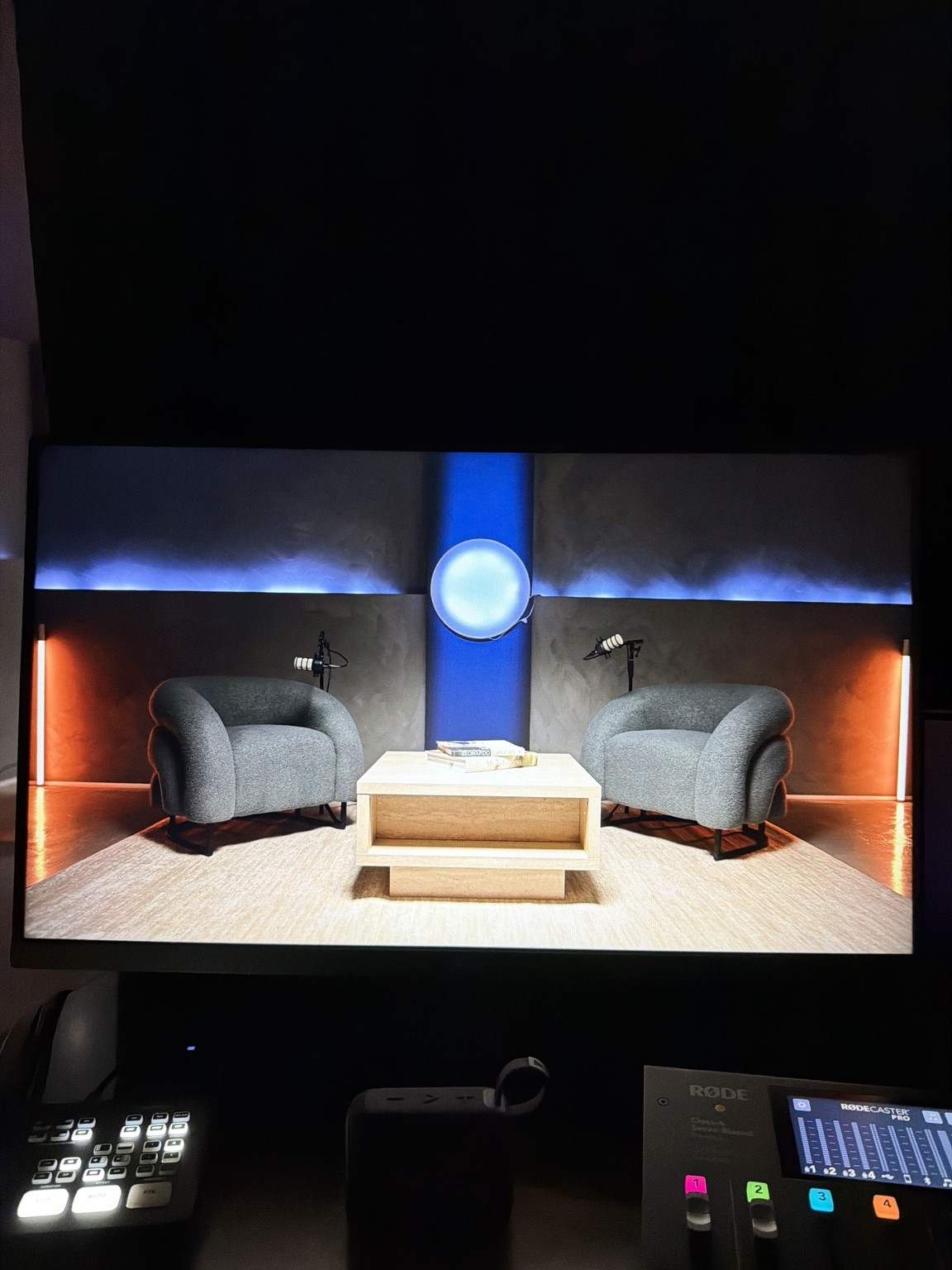 A production monitor shows the lounge set with blue and orange accent lighting.
