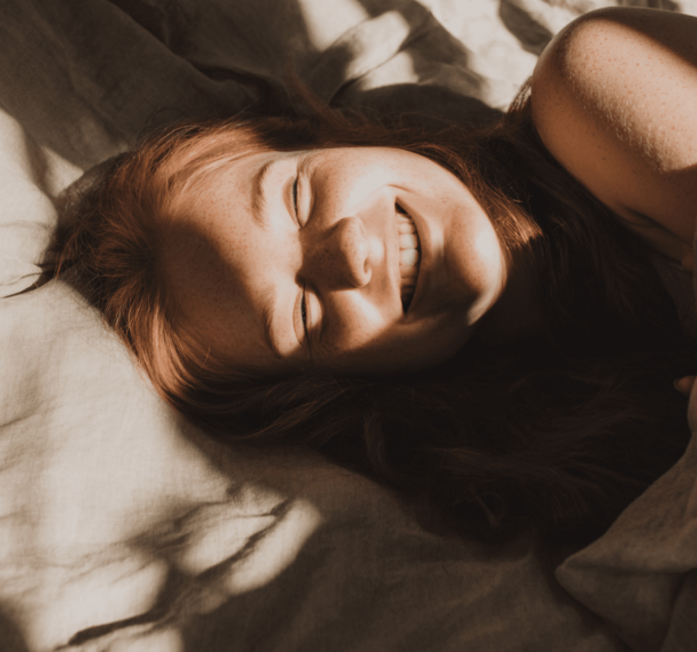 Relaxed guest lying in bed with soft morning light creating a calm and comfortable atmosphere