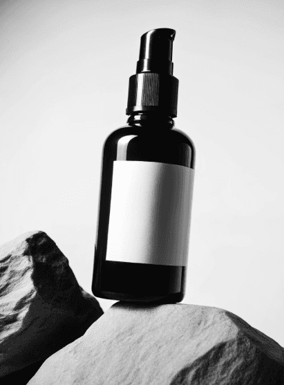A sleek black spray bottle with a blank label sits atop textured gray stones, evoking a minimalist and natural aesthetic in a serene, monochrome setting.
