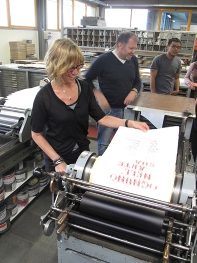 A photo of a group of people working at a printing press.