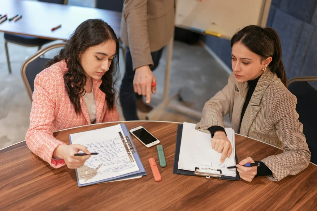 Two colleagues reviewing documents and notes together at table