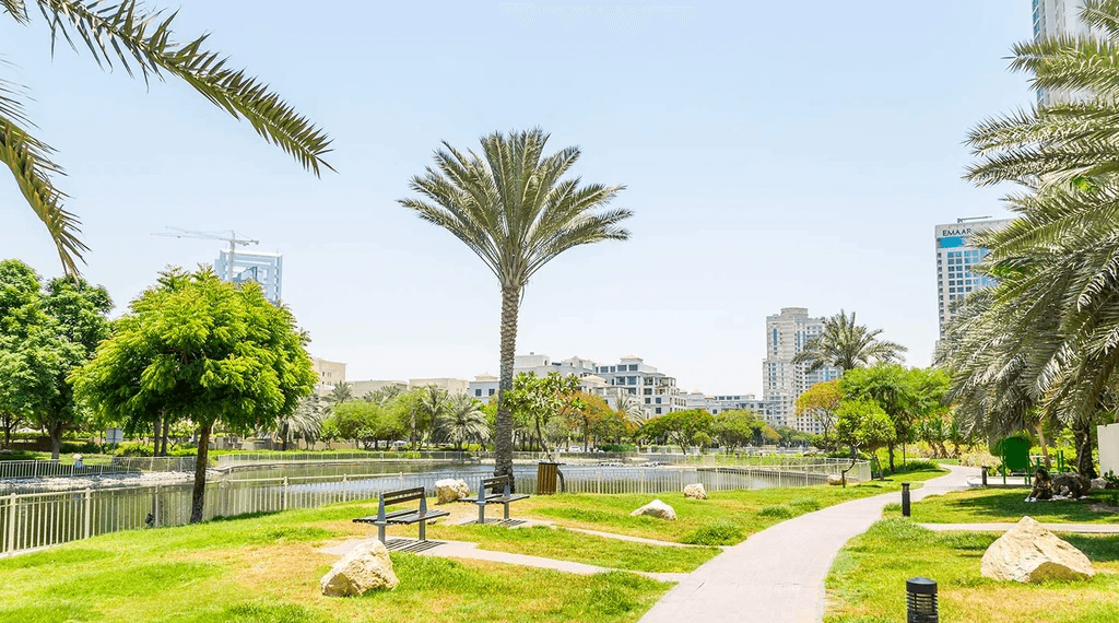 A scenic view of The Greens Community beach, featuring golden sand, gentle waves, and a clear blue sky.