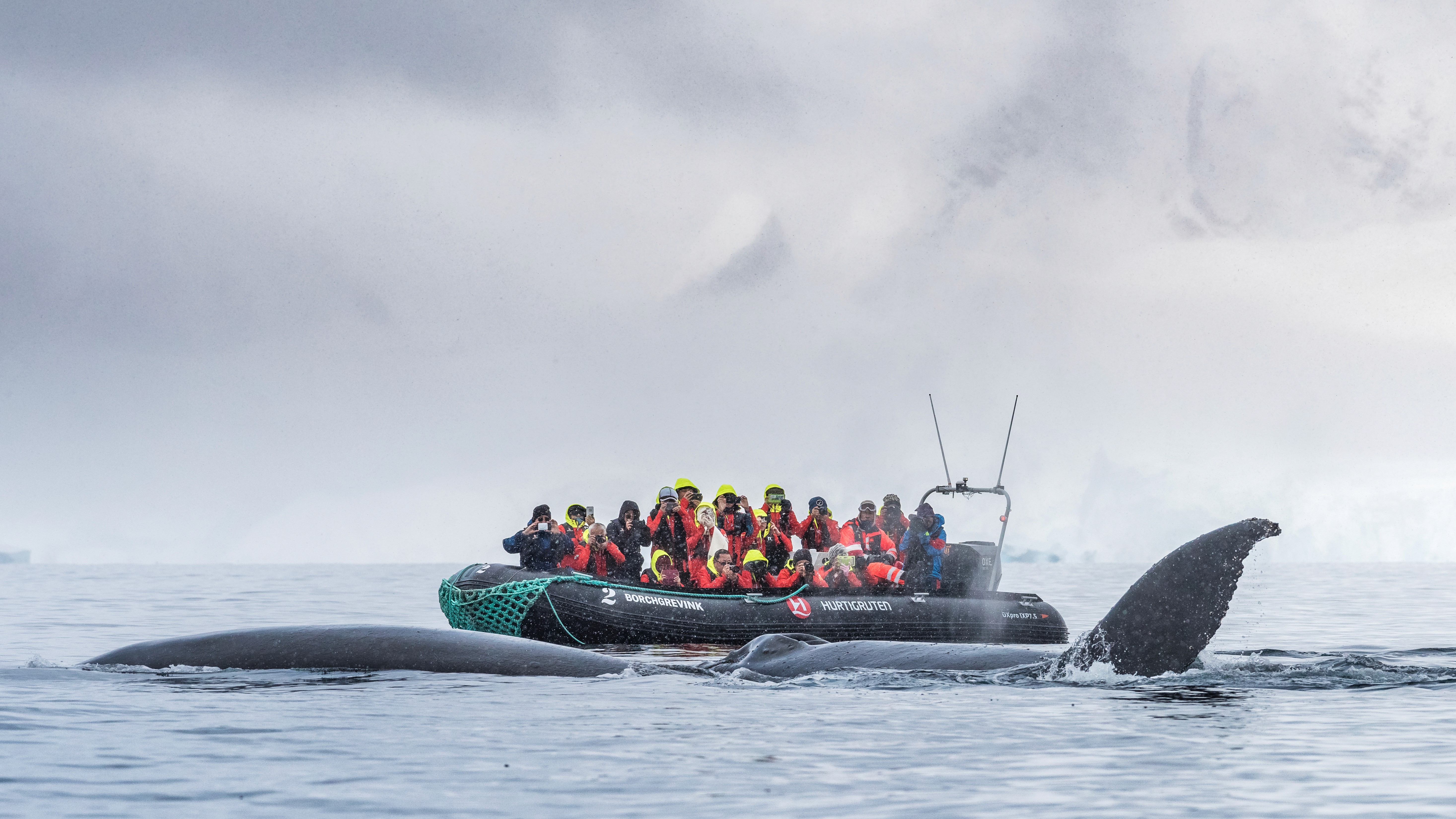 The photograph captures a group of people on a small inflatable boat in a vast, open body of water.