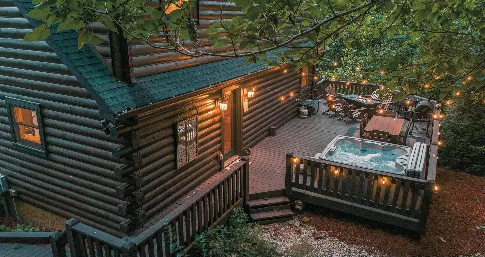 Cabin deck with a hot tub lit at dusk