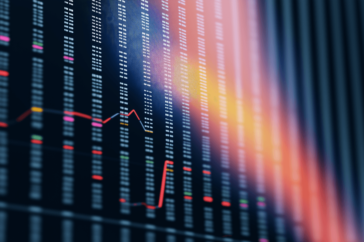 Abstract image of financial graphs on dark background with colorful lines and candlestick patterns indicating market trends.