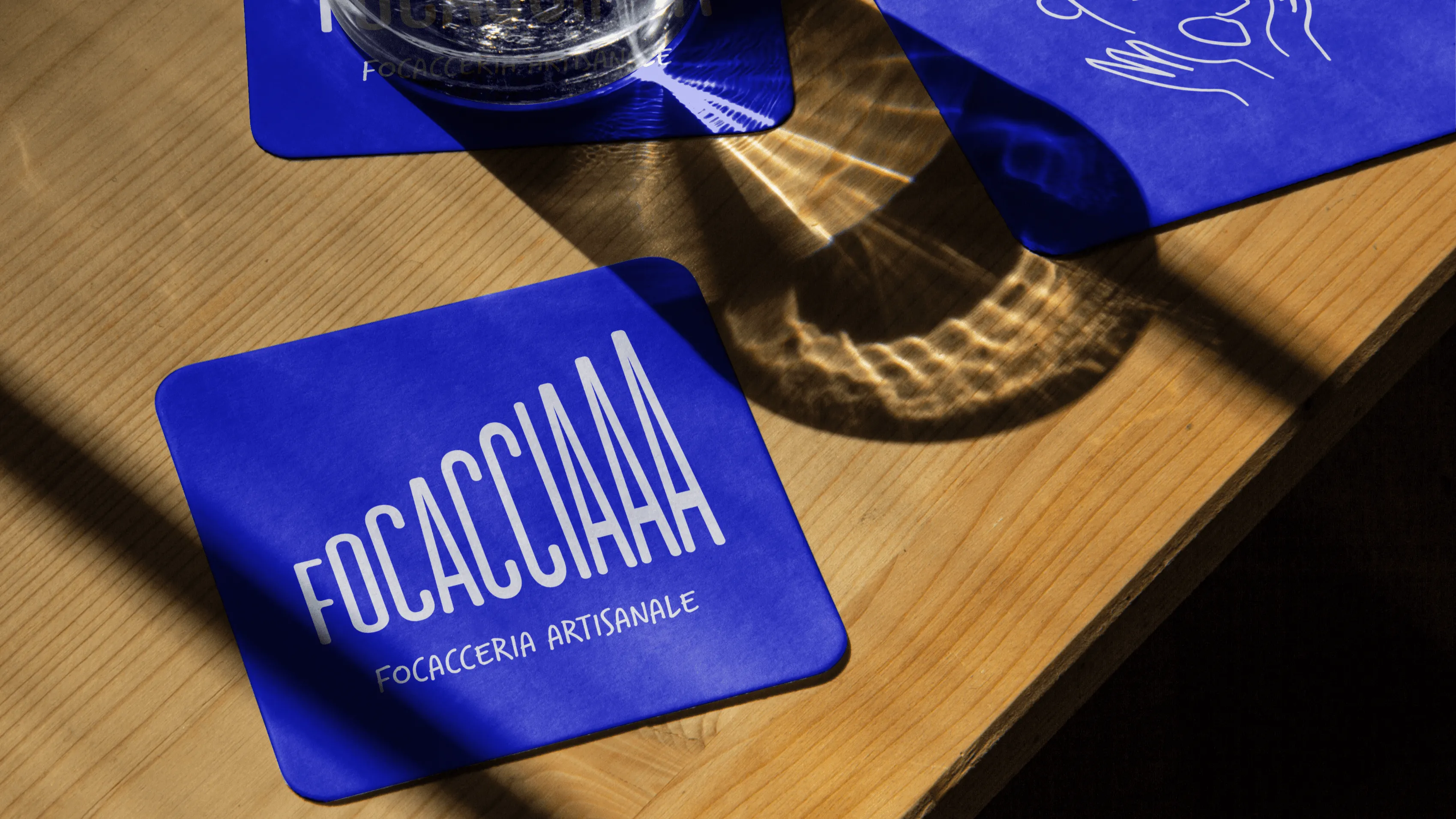 Sous-verres Focacciaaa bleus avec logo blanc sur table bois