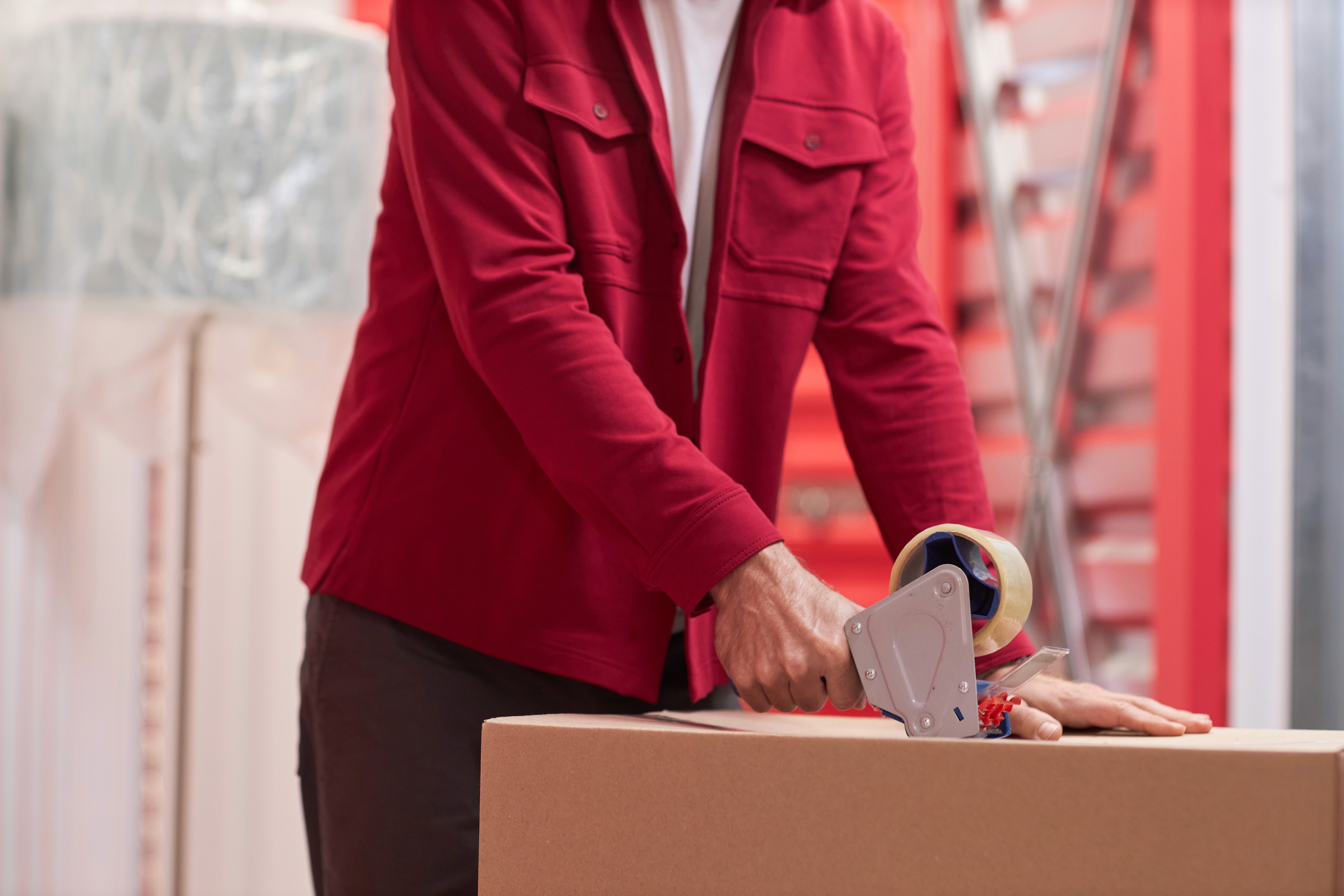 Man taping a box in a self-storage unit, following self storage tips for efficient packing, by ARENA Storage