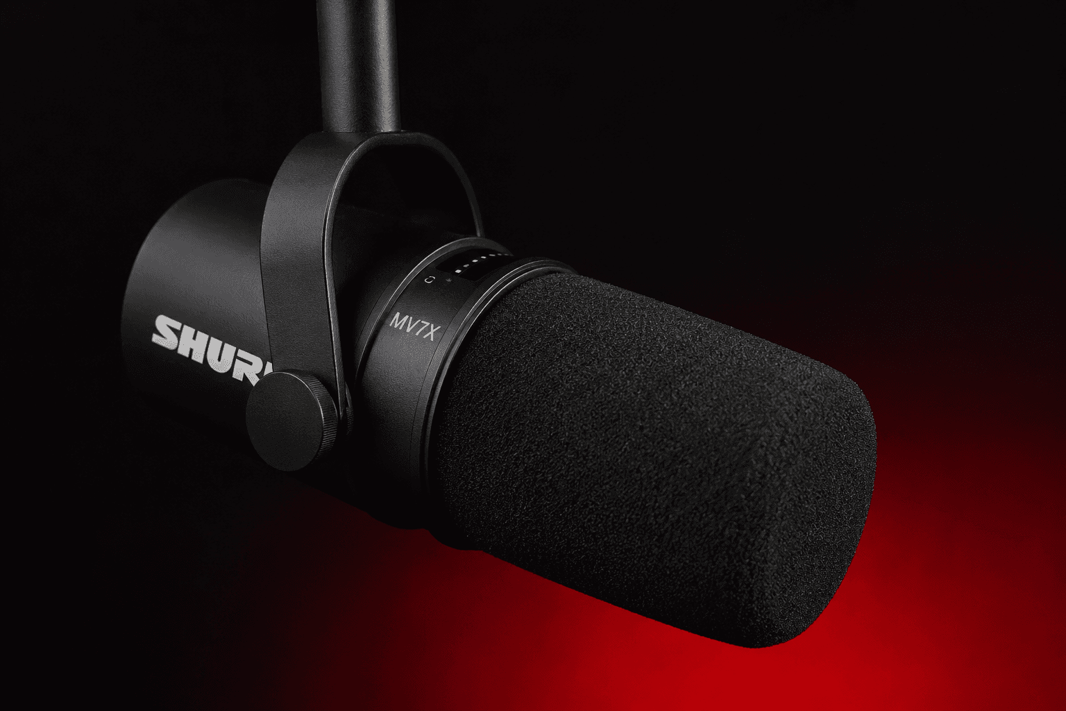 Close-up product photo of a black Shure MV7X podcast microphone with a minimalist black and red background, featuring dramatic studio lighting and a modern professional audio setup aesthetic.