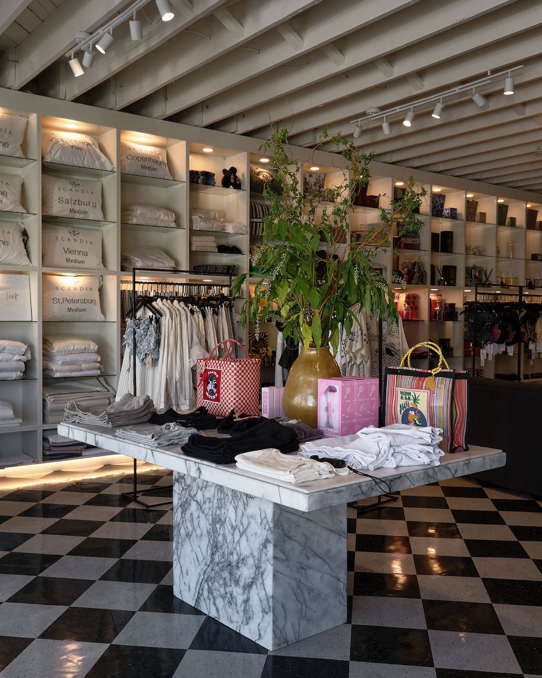 Forte Deux fashion boutique interior with marble display table, curated clothing and accessories, and checkered retail flooring.