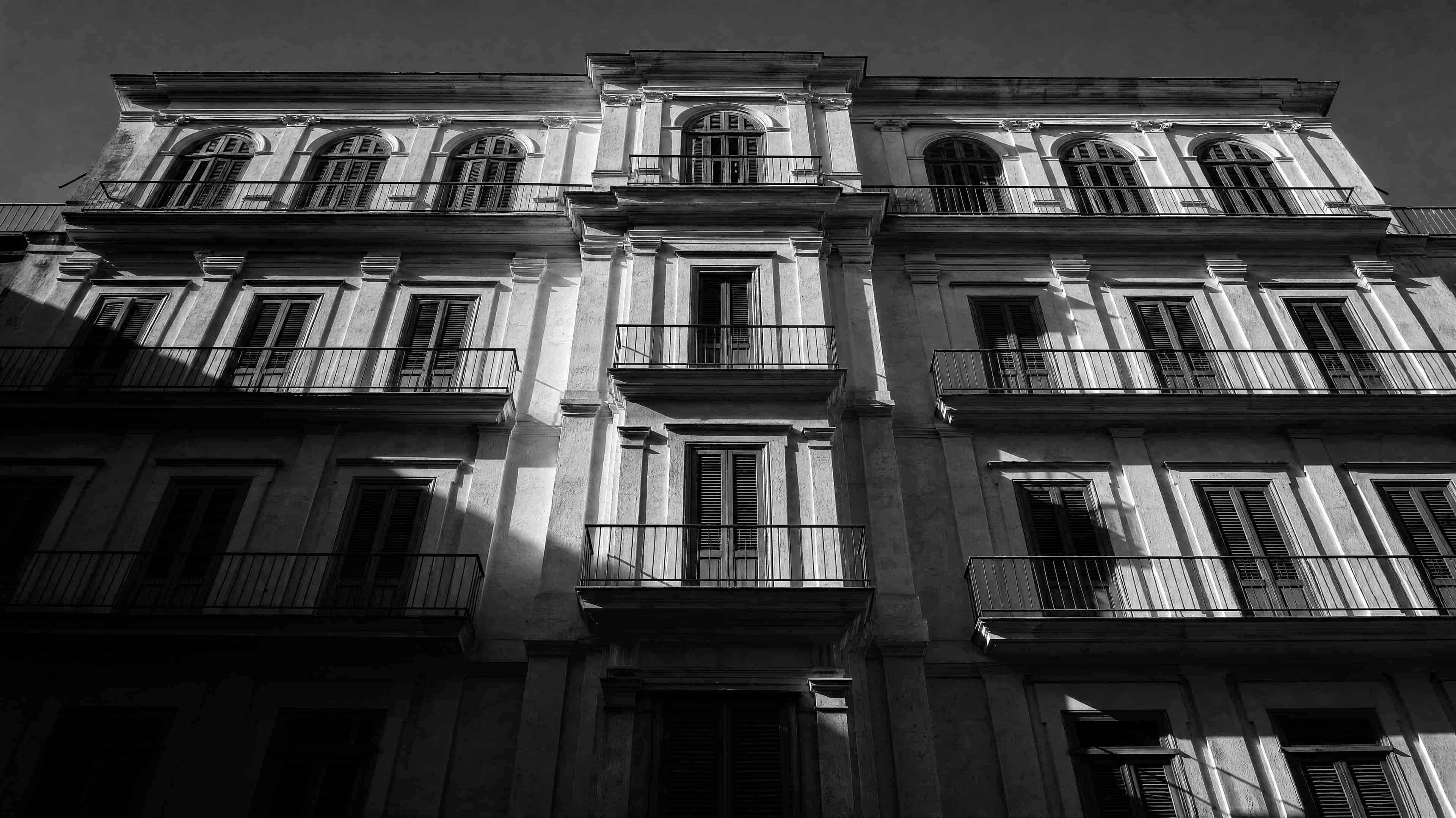 Südeuropäische Altbaufassade mit schmiedeeisernen Balkonen und Fensterläden, von unten fotografiert