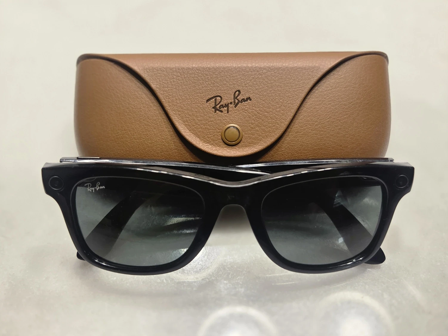 Black Ray-Ban Meta smart glasses from the 2023 generation in front of their brown charging case.