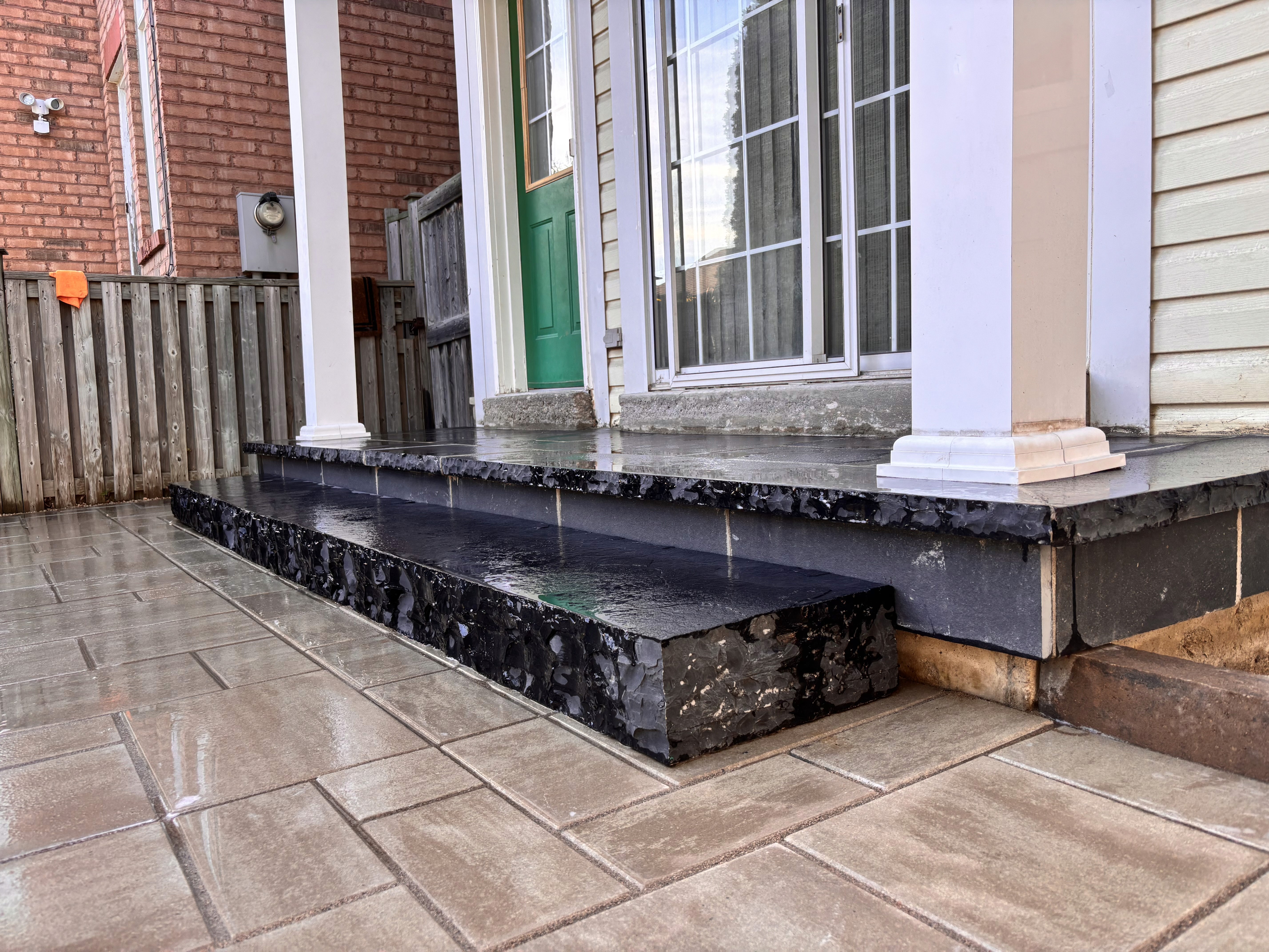 A ramp leading up to a porch, with steps on either side and a wooden floor, in a residential area.
