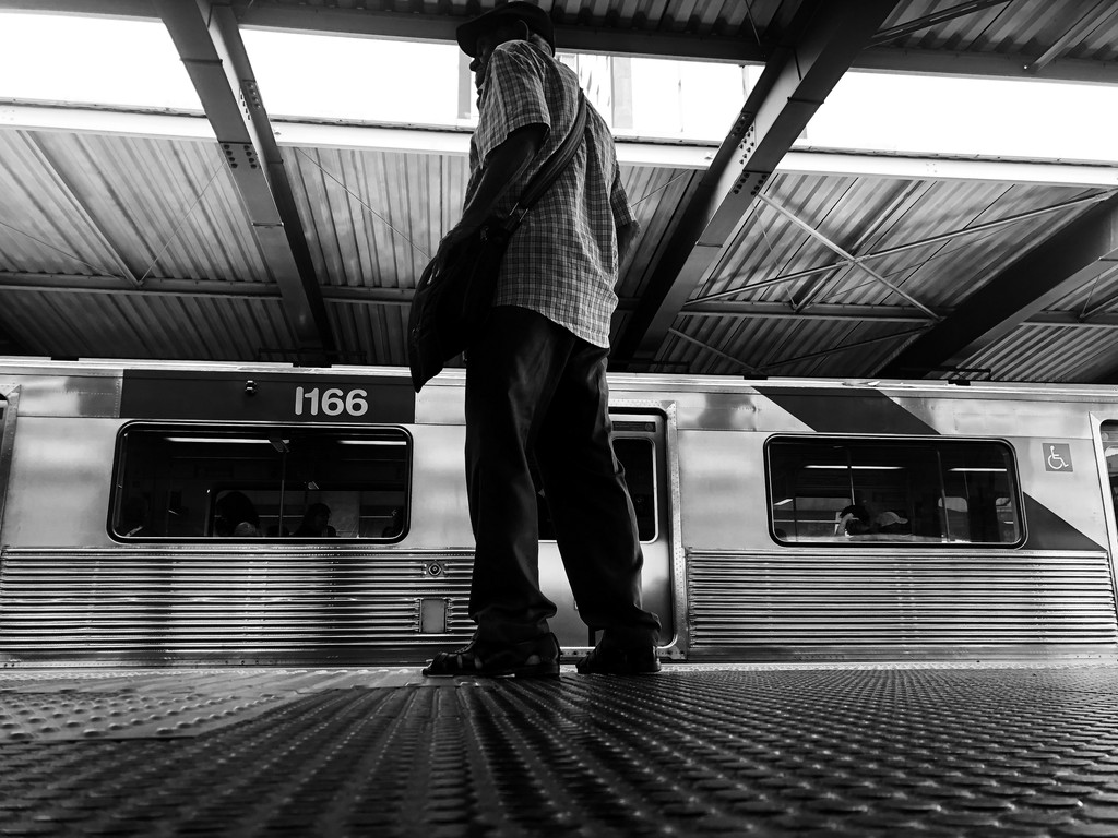 black white image in frog perspective showing a man waiting on the subway.