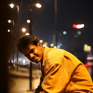 Portrait of Dev Raman smiling on a city street at night