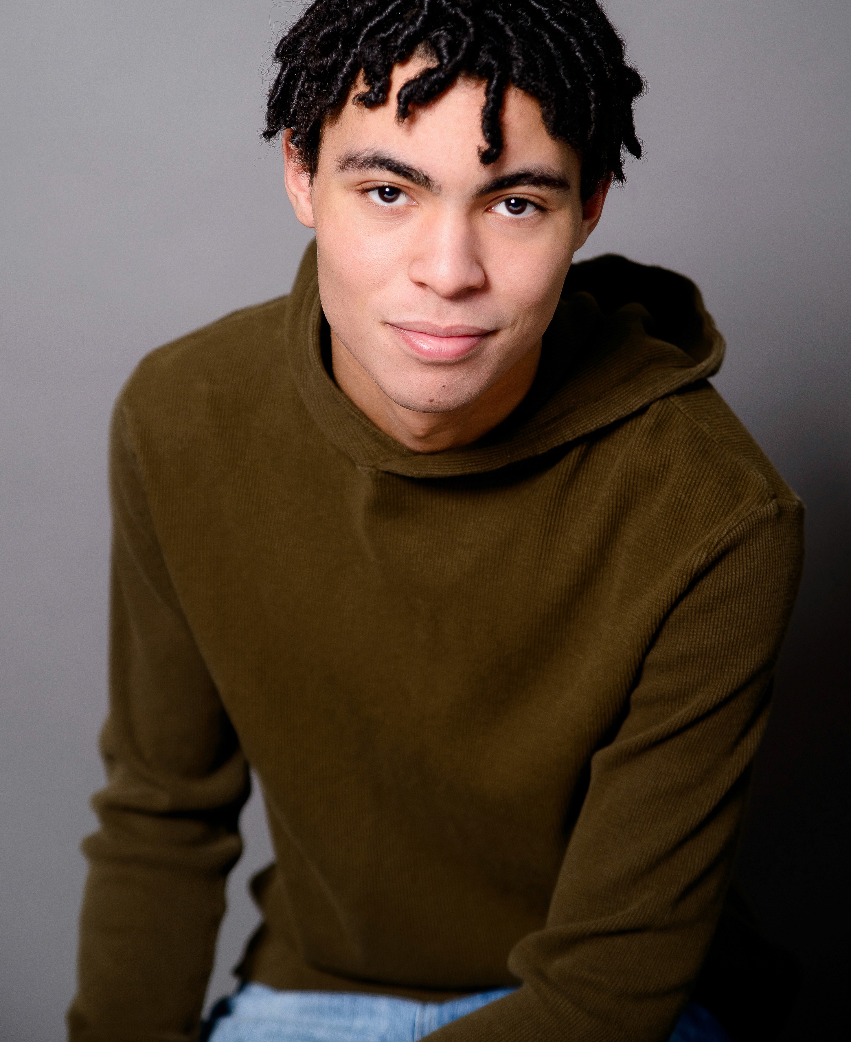 Young filmmaker and podcaster headshot photographed on gray in studio