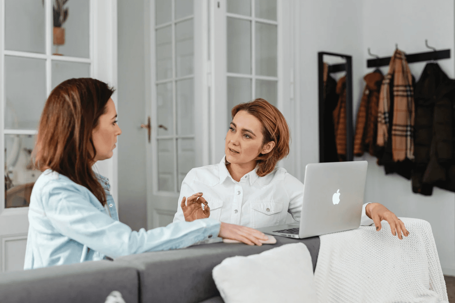 Two women discussing strategy next to a laptop, showing how specialist-only Amazon ad setups struggle to react quickly during peak-demand surges.