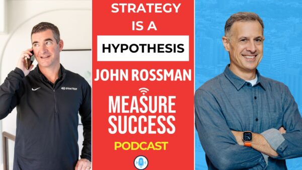 Woman with blonde hair smiling while talking on the phone at a desk with a laptop and papers.