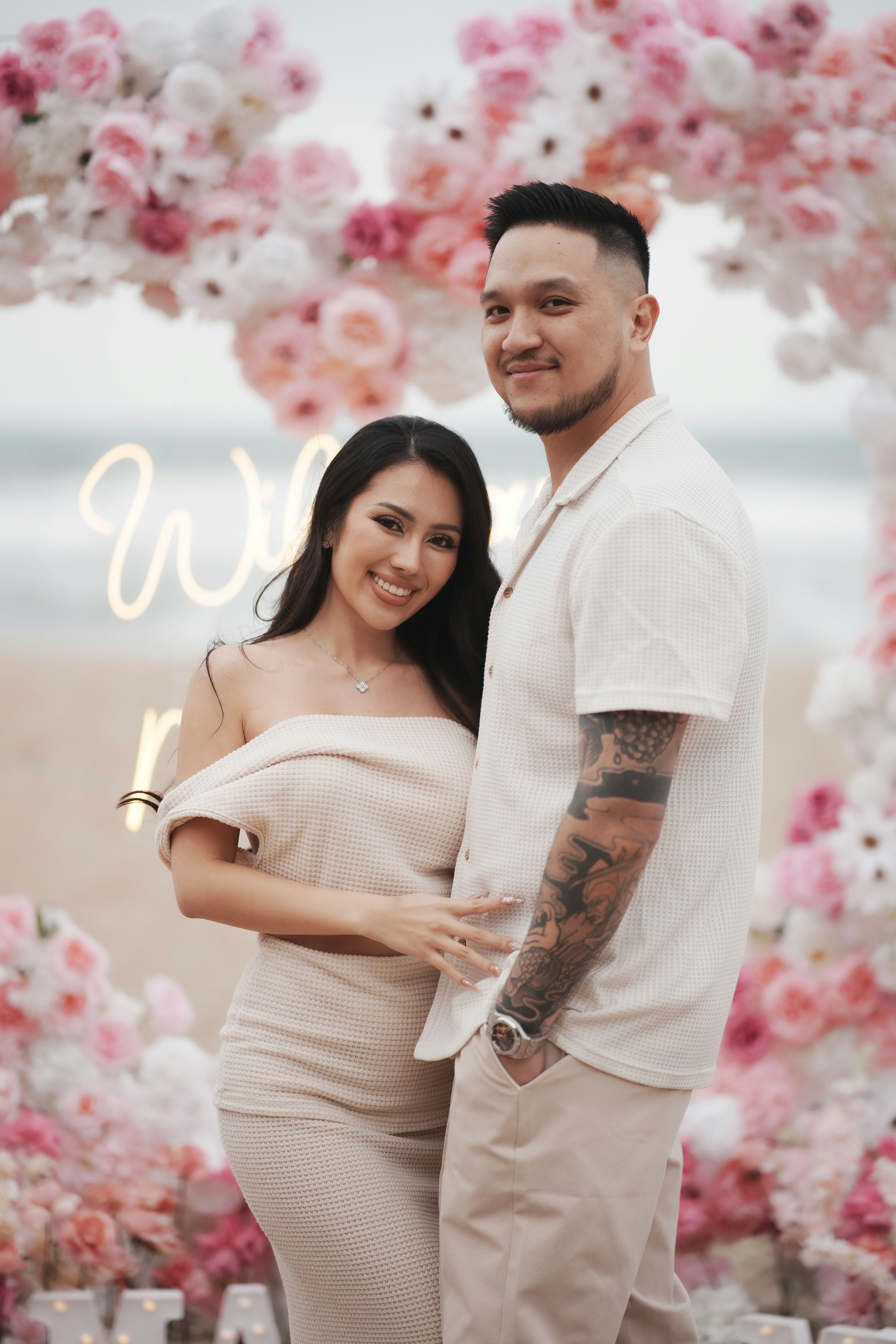 Smiling female therapist with short gray hair, wearing a brown top and a purple shawl, surrounded by a cozy background.