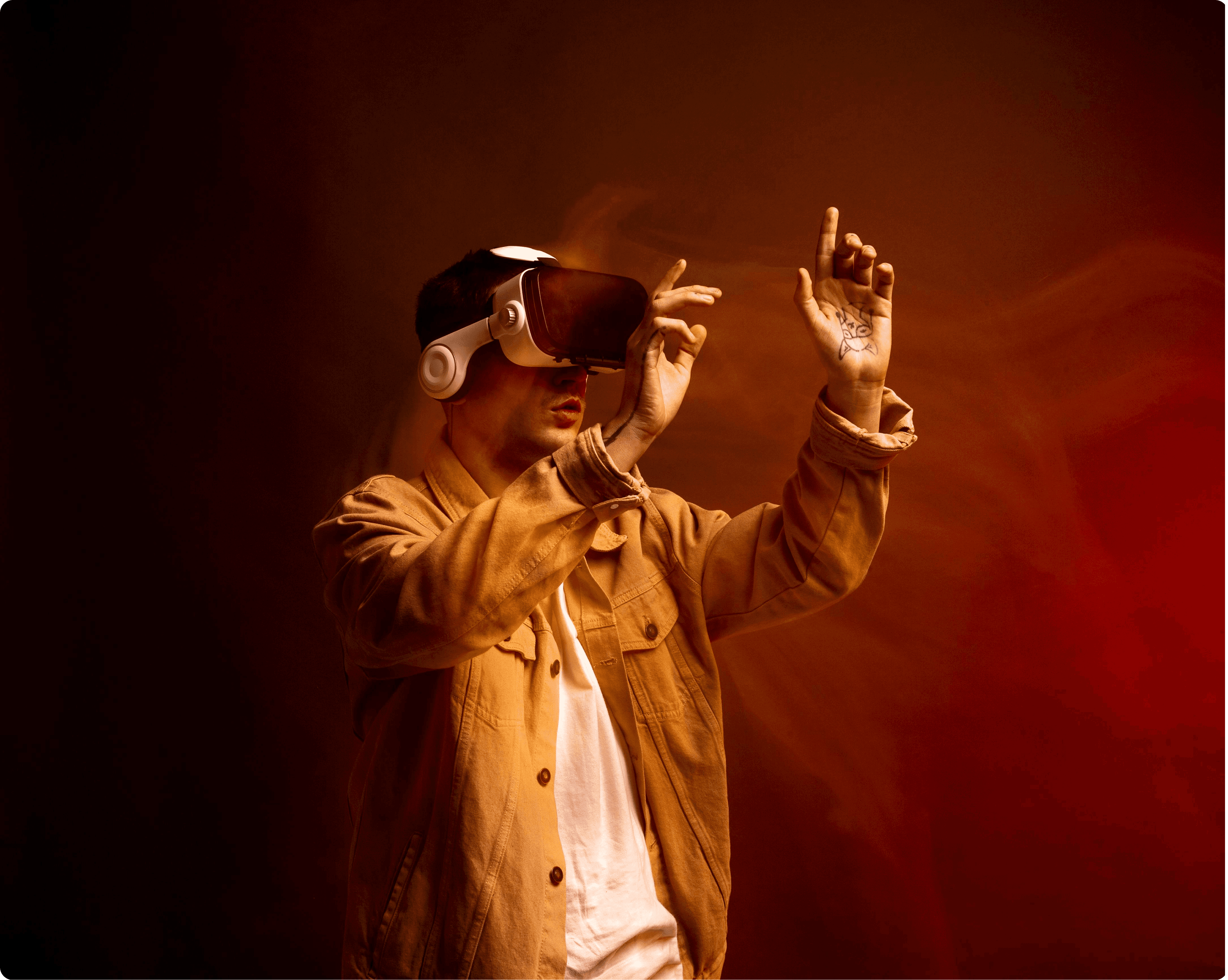 A cinematic portrait of a man wearing a white VR headset and a mustard yellow denim jacket, interacting with a virtual interface using his hands. The scene is set against a moody, smoky orange and amber background with dramatic studio lighting that highlights his movements.
