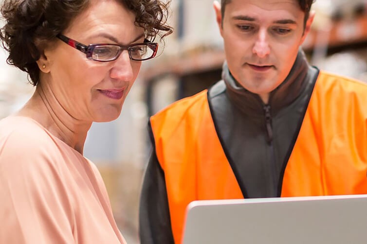 Warehouse staff reviewing delivery data on laptop