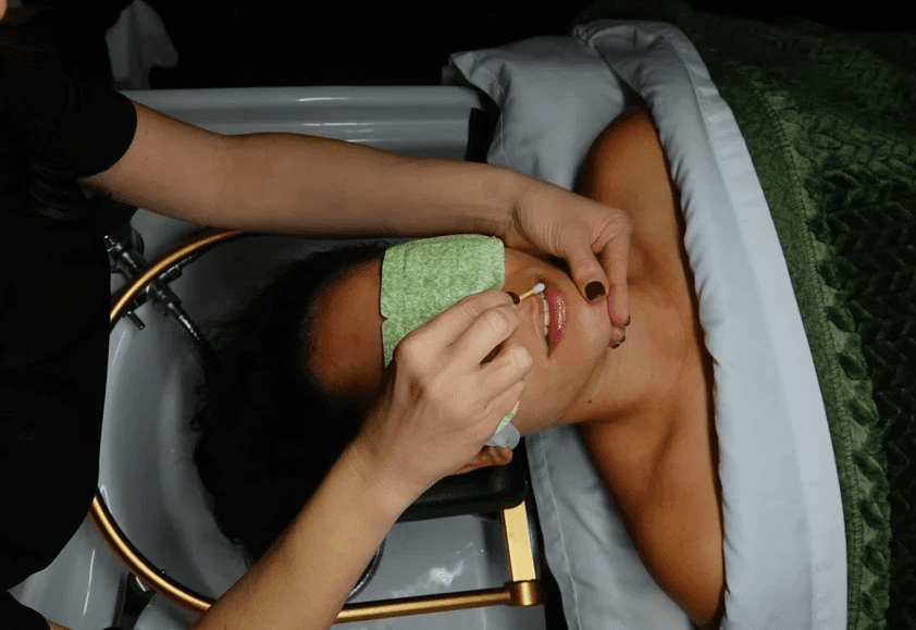 Sylvia applying lip treatment to client's lips. 