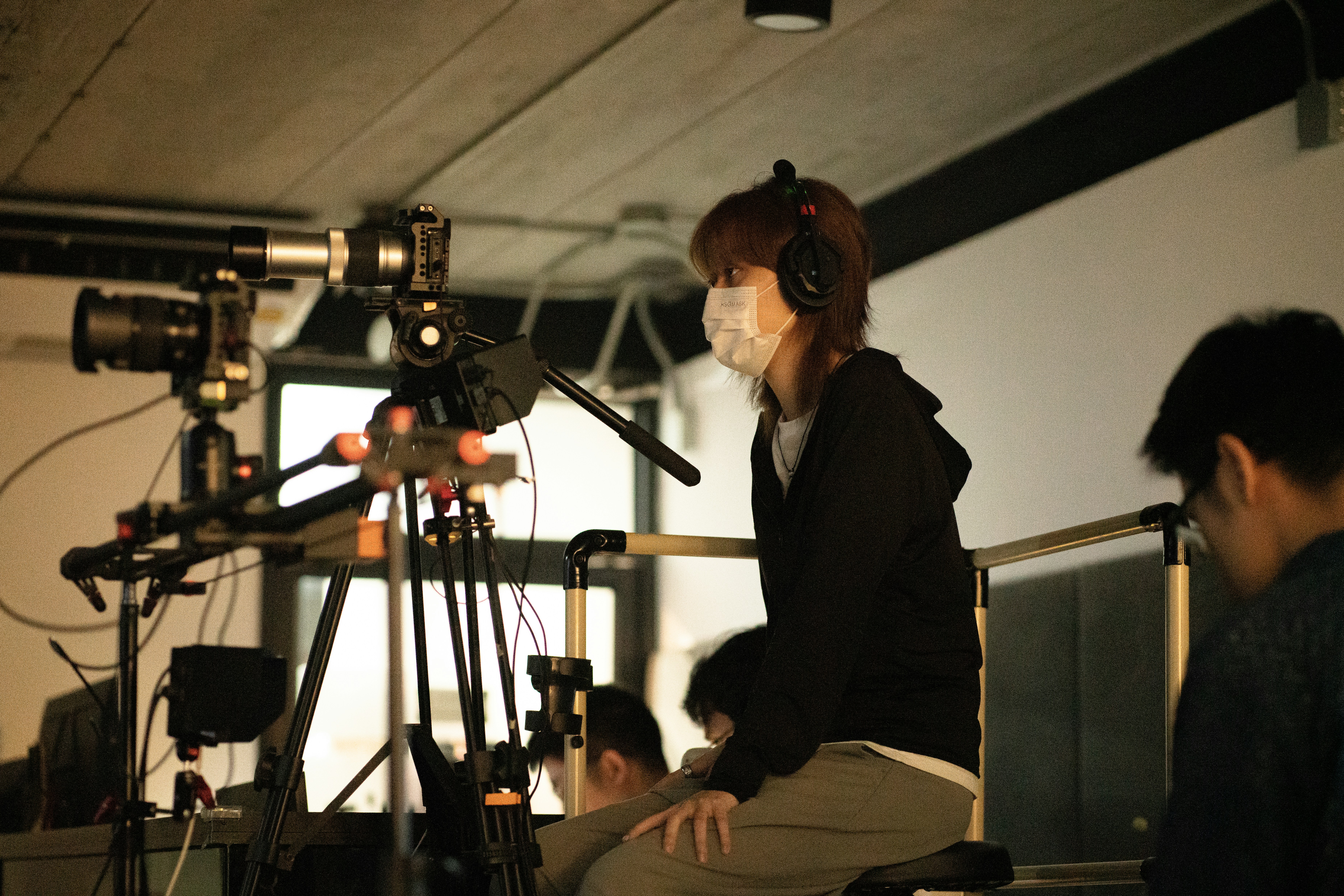 Filmmaker wearing headphones and mask with camera equipment