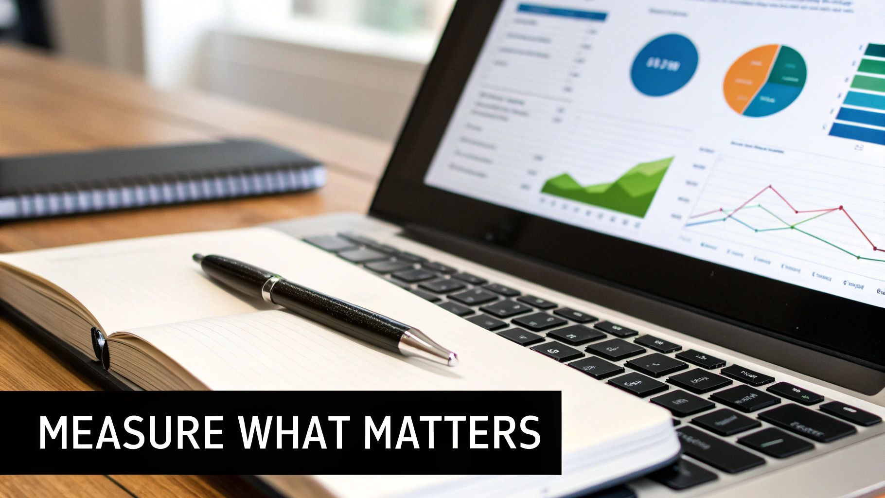 A laptop displaying data analytics charts next to an open notebook and pen, emphasizing performance measurement.