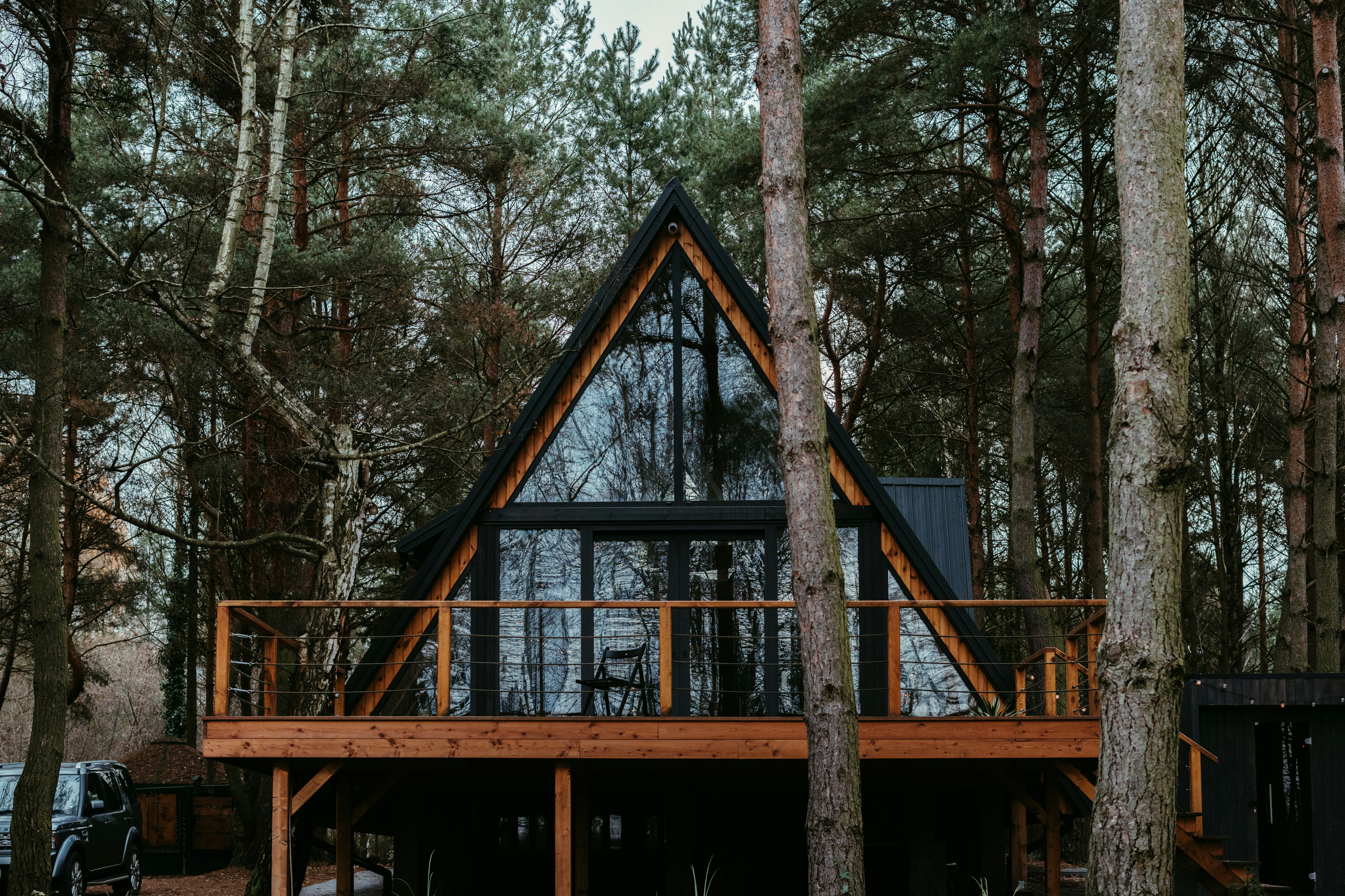 A low, modern wood house with large windows sits on a grassy hill.
