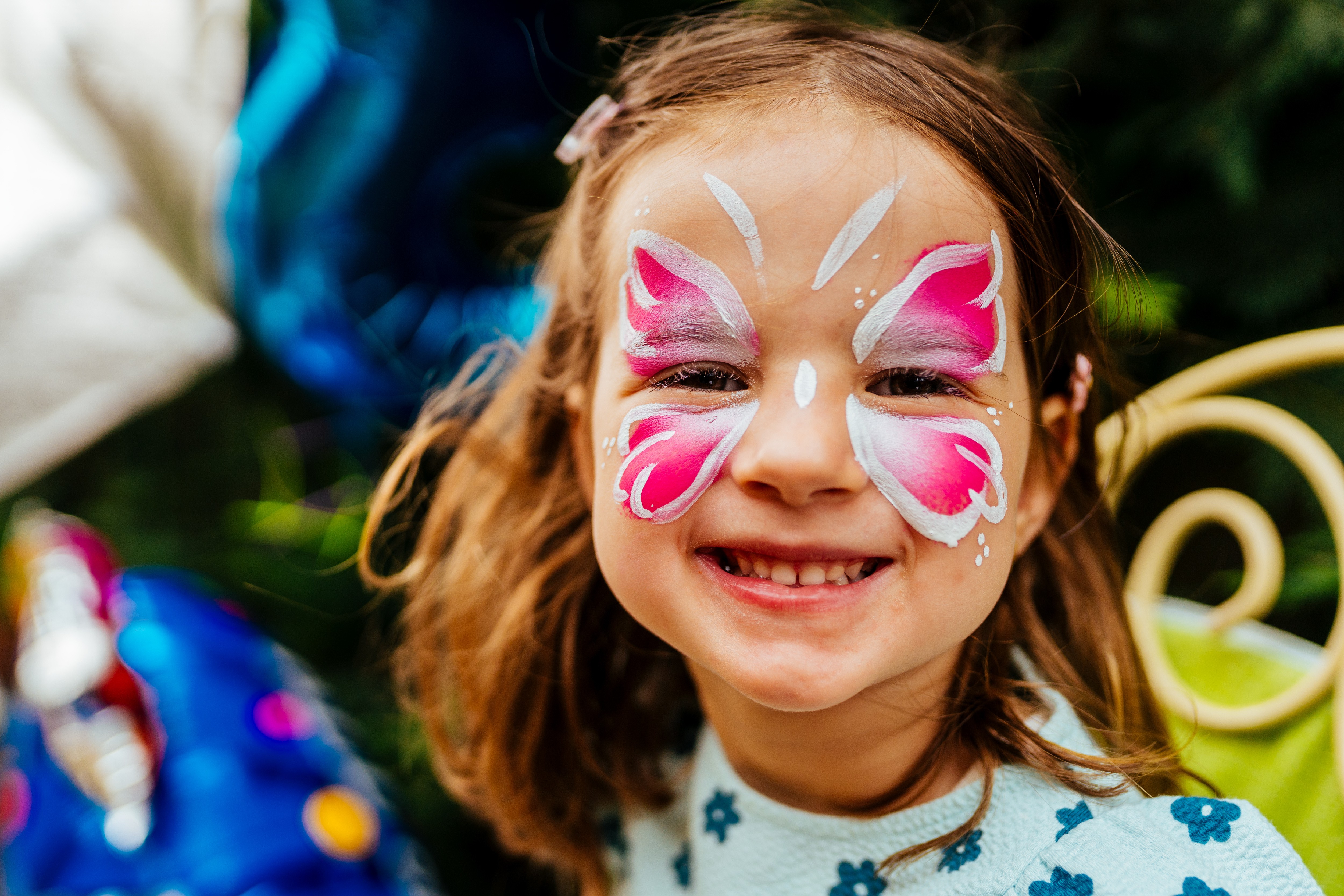 Smiling child with colourful butterfly face paint during a family fun day