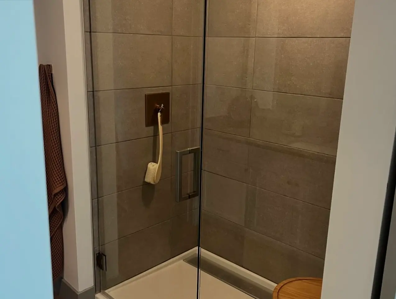Streak-free glass shower door and polished chrome handle after a professional home cleaning service.
