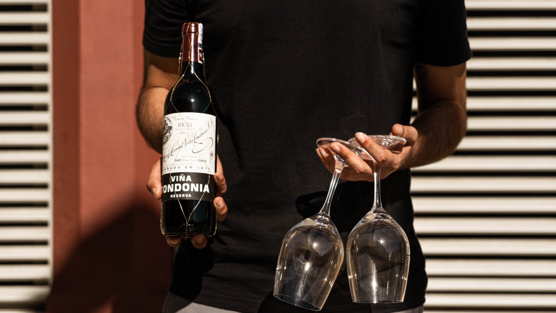 Sommelier holding a bottle of wine and glasses during a Barcelona food and wine experience.
