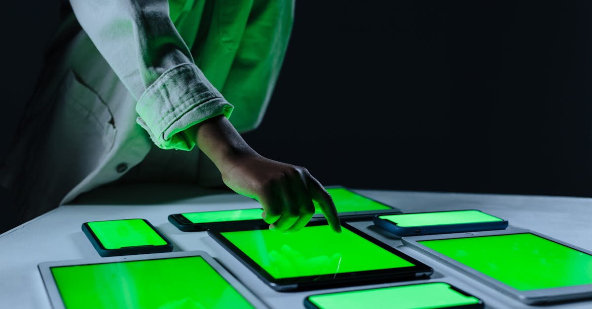 Hand interacting with multiple digital tablets on a green screen setup indoors.