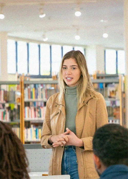Estudiante universitaria hablando con compañeros en biblioteca