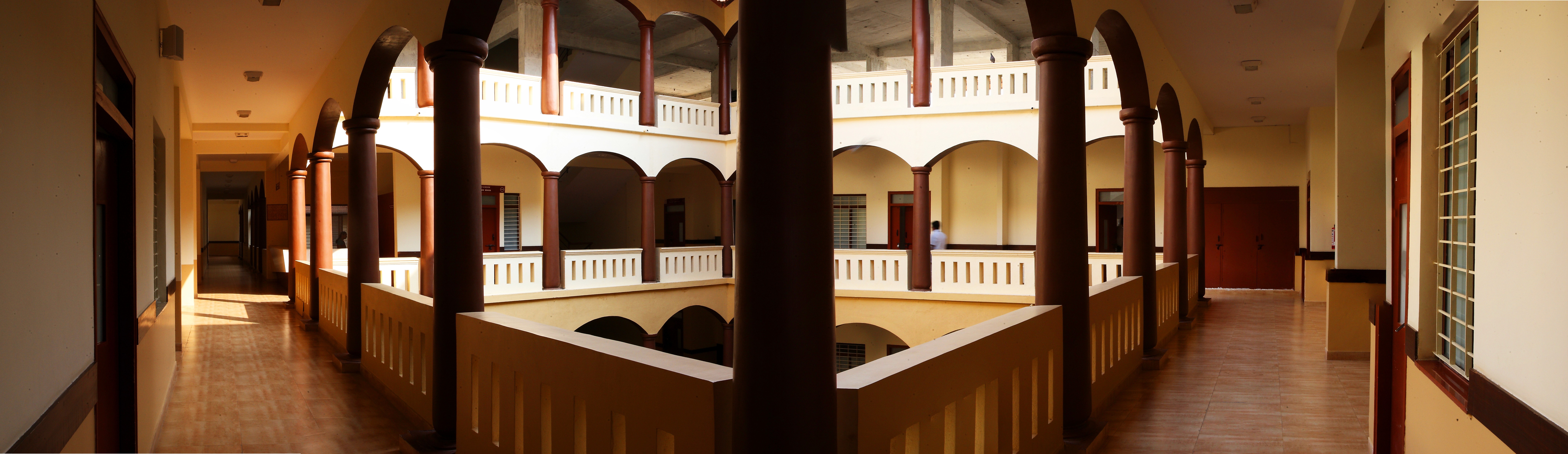 A winding road cuts through rocky terrain, surrounded by patches of green grass and illuminated by sunlight.