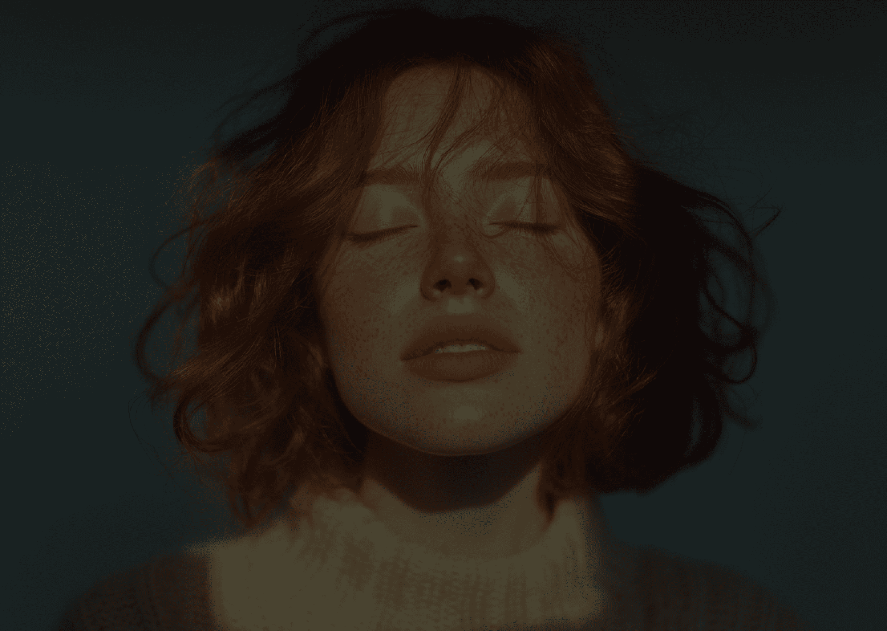 Close-up of a woman with her eyes closed, her hair covering part of her face. She appears serene and peaceful.