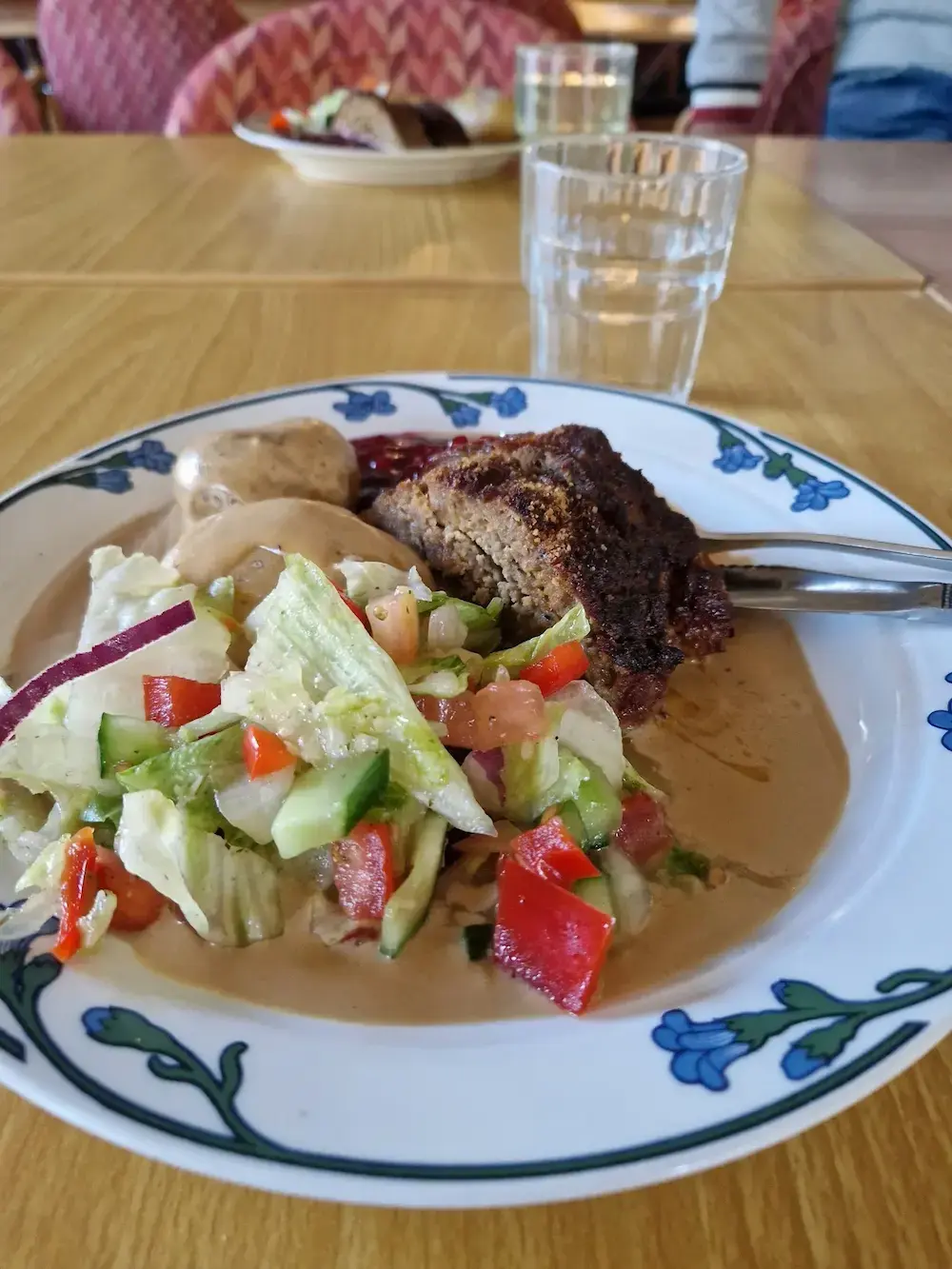 Tallrik med varm mat bestående av köttbullar, potatis och sallad.