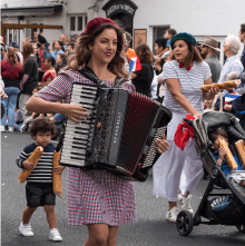 Lucy strolling through a parade with her accordion, wearing a beret.