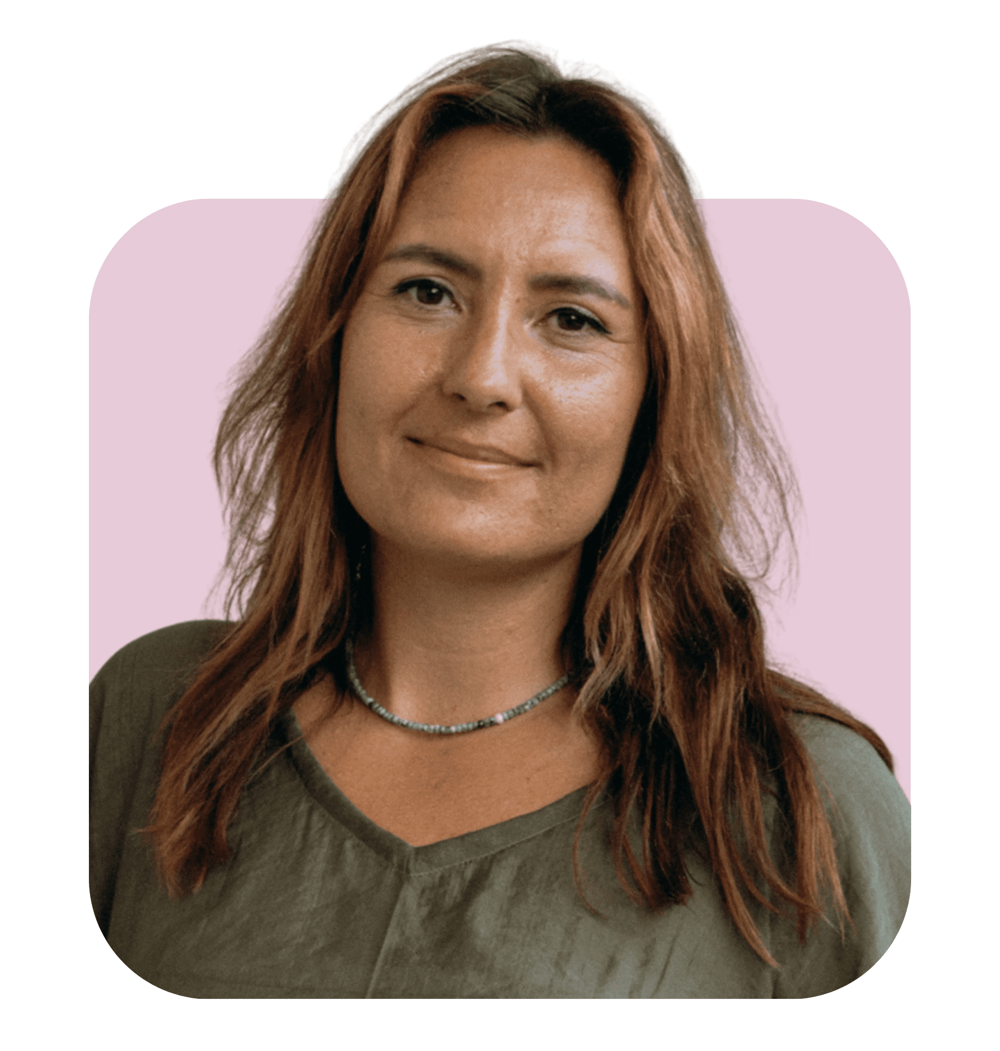 A woman with long brown hair smiles, wearing a green shirt, against a soft pink background.