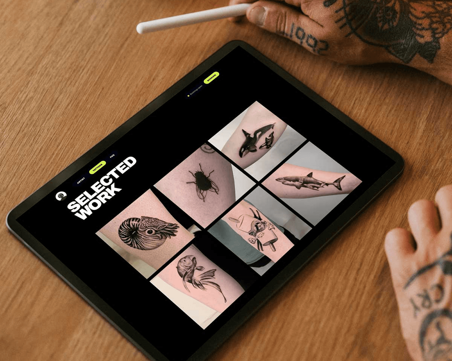 I pad auf holztisch liegend mit Galerie ansicht einer webseite tättowierete Hand mit Apple pencile in der Ecke