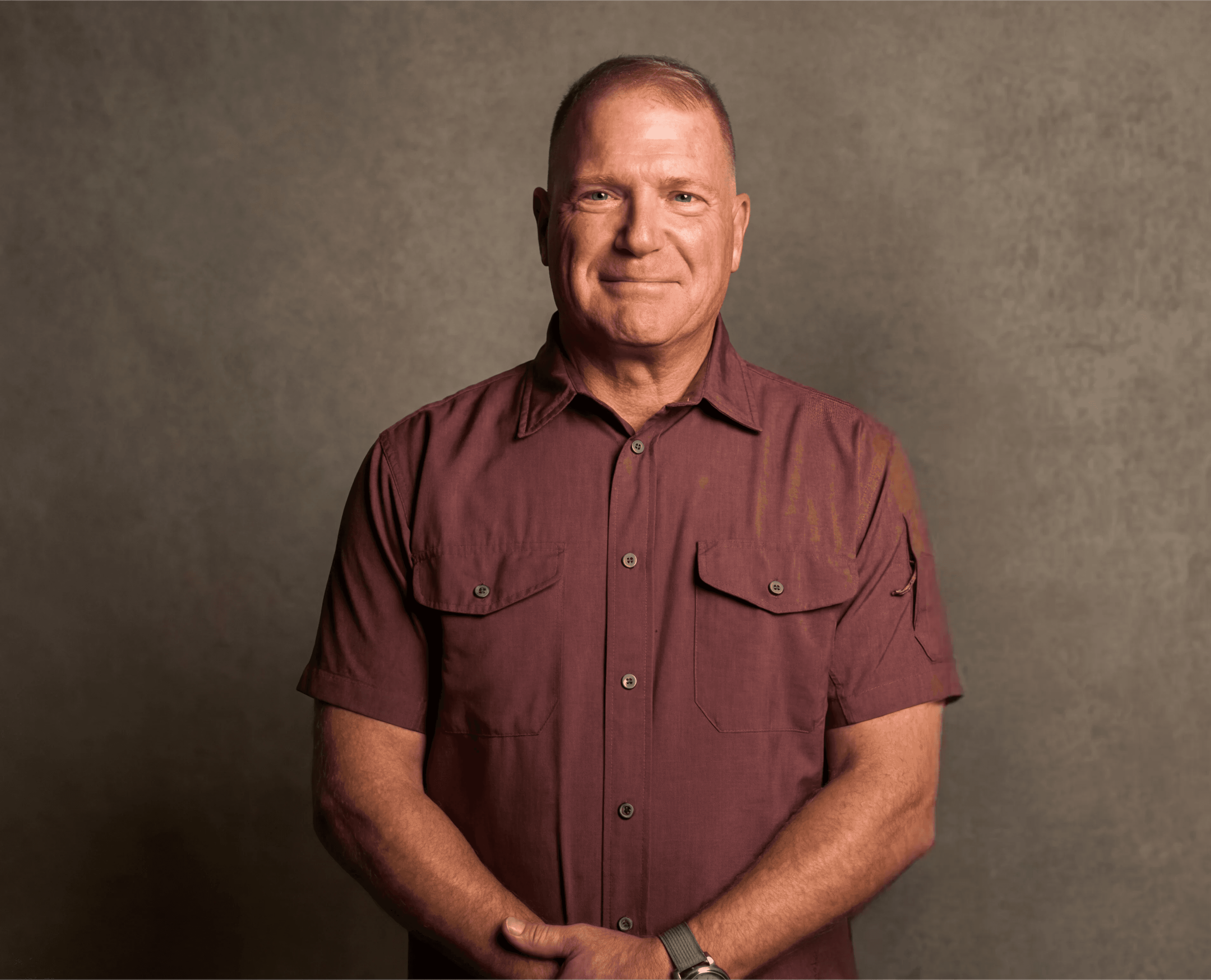 Man with curly hair wearing brown hat and dark shirt.