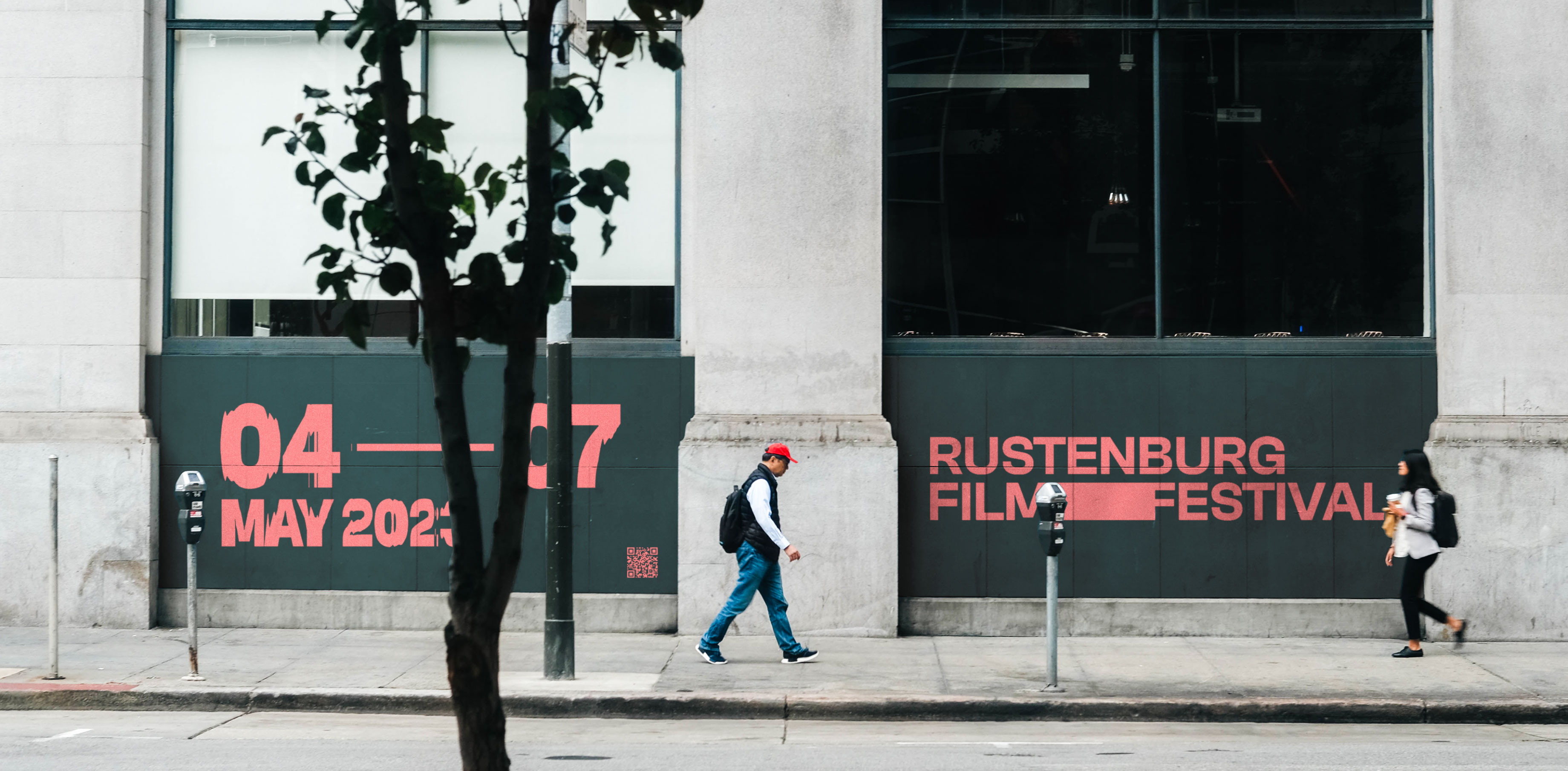 Wide shot of a man wearing a red cap, walking past one of the RFF ad banners