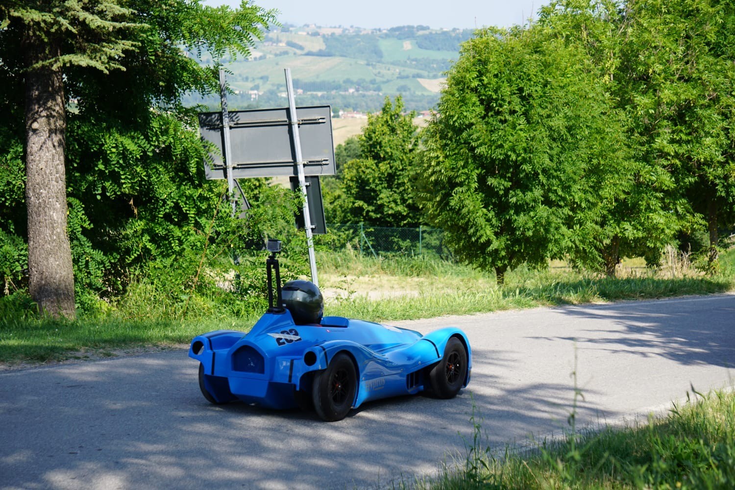 Caisse à savon bleue numéro 203 sur la route avec paysage de collinesGallery