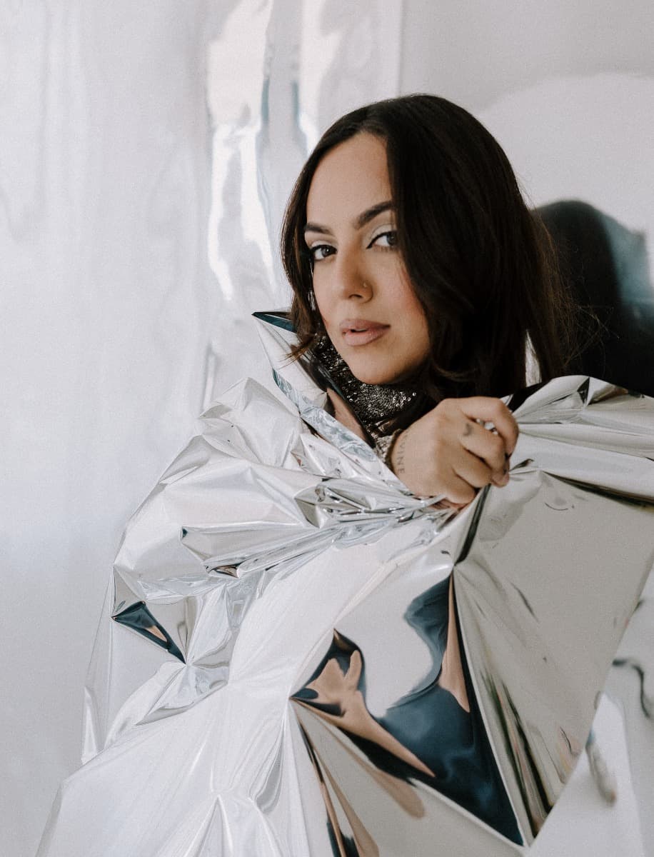 A model wrapped in reflective Mylar material, styled in a sparkling silver top, photographed during a creative shoot at Revelator Studio, a Shreveport natural light studio.