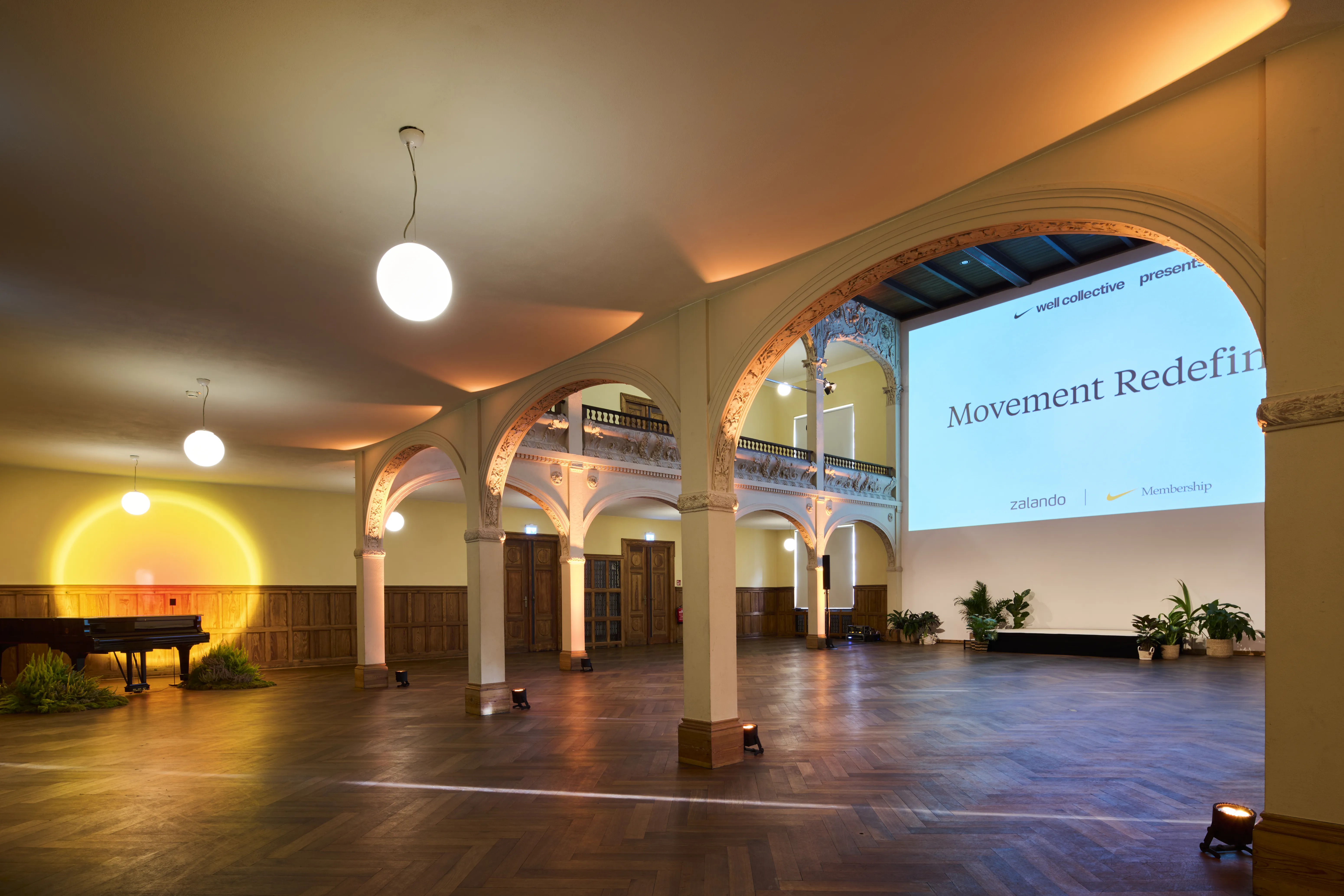Arched historic hall with Movement Redefined screen, piano and sunset light projection.