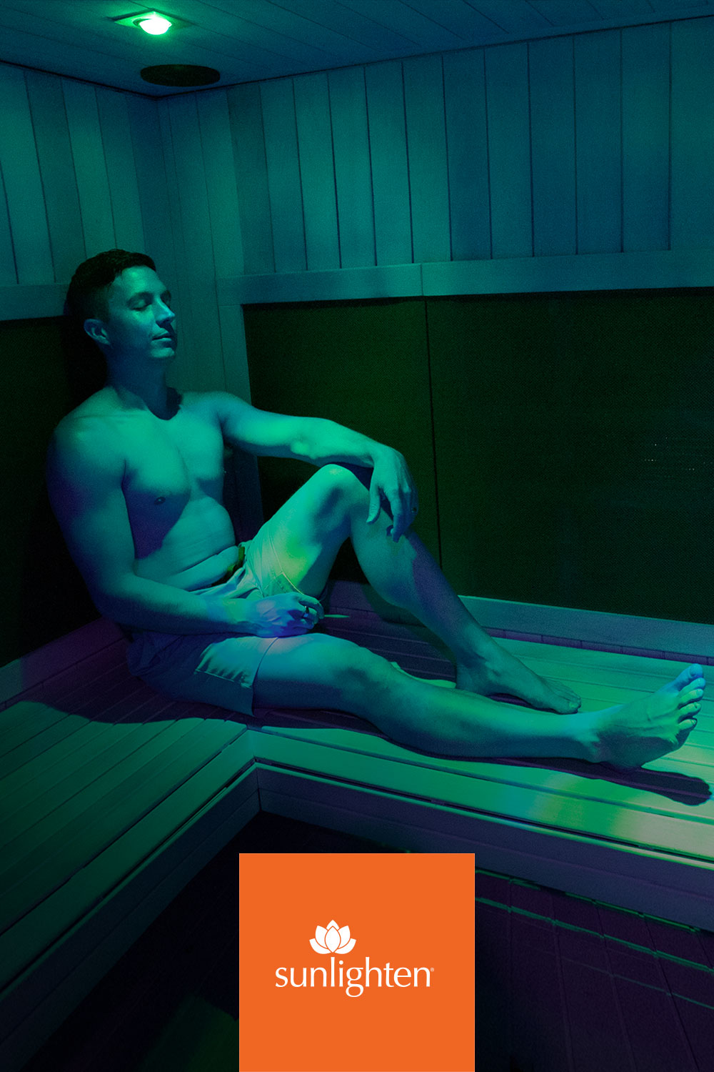 Member bathed in colored chromotherapy light inside the infrared sauna