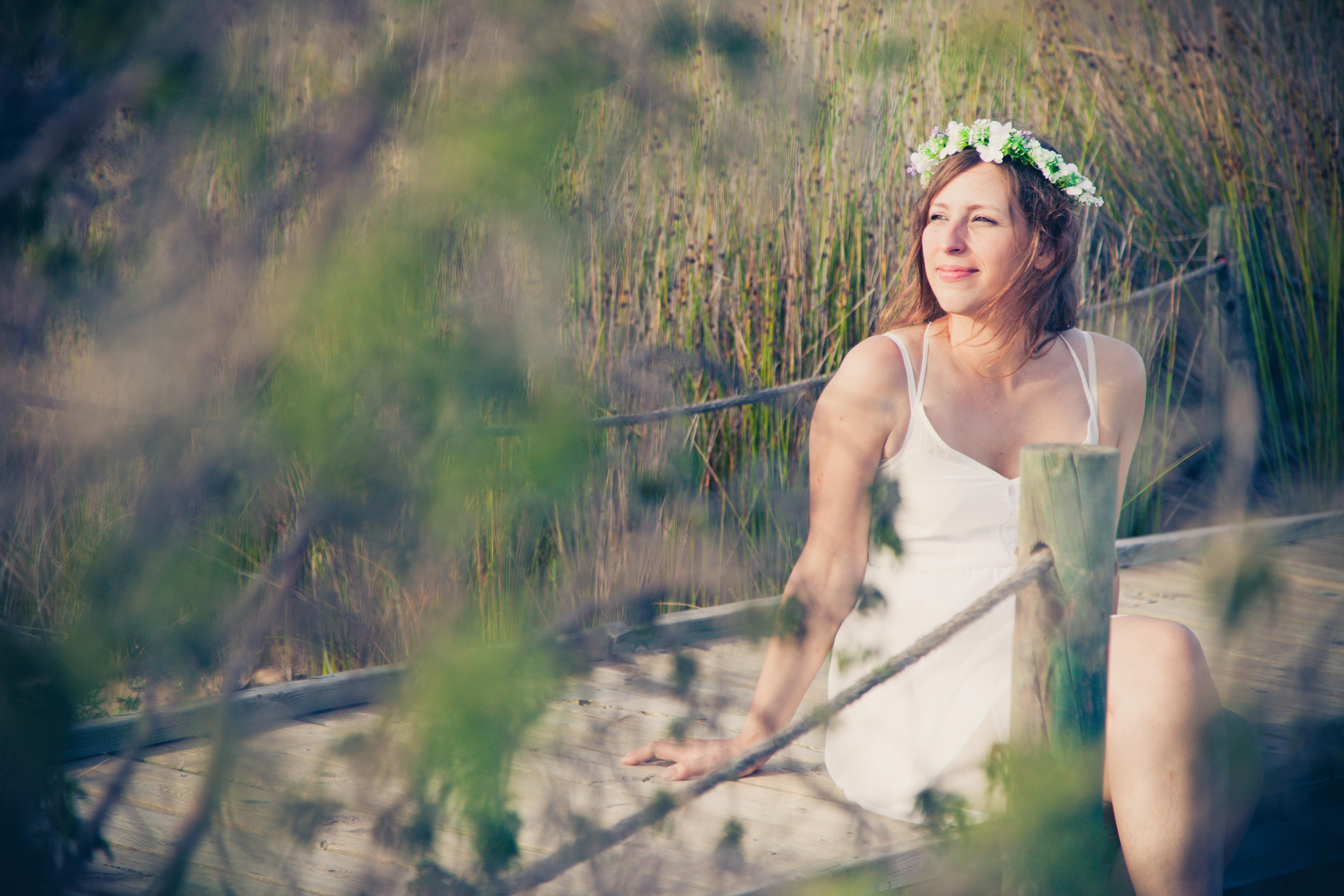 Chica posando con un vestido blanco en la playa rodeada de plantas