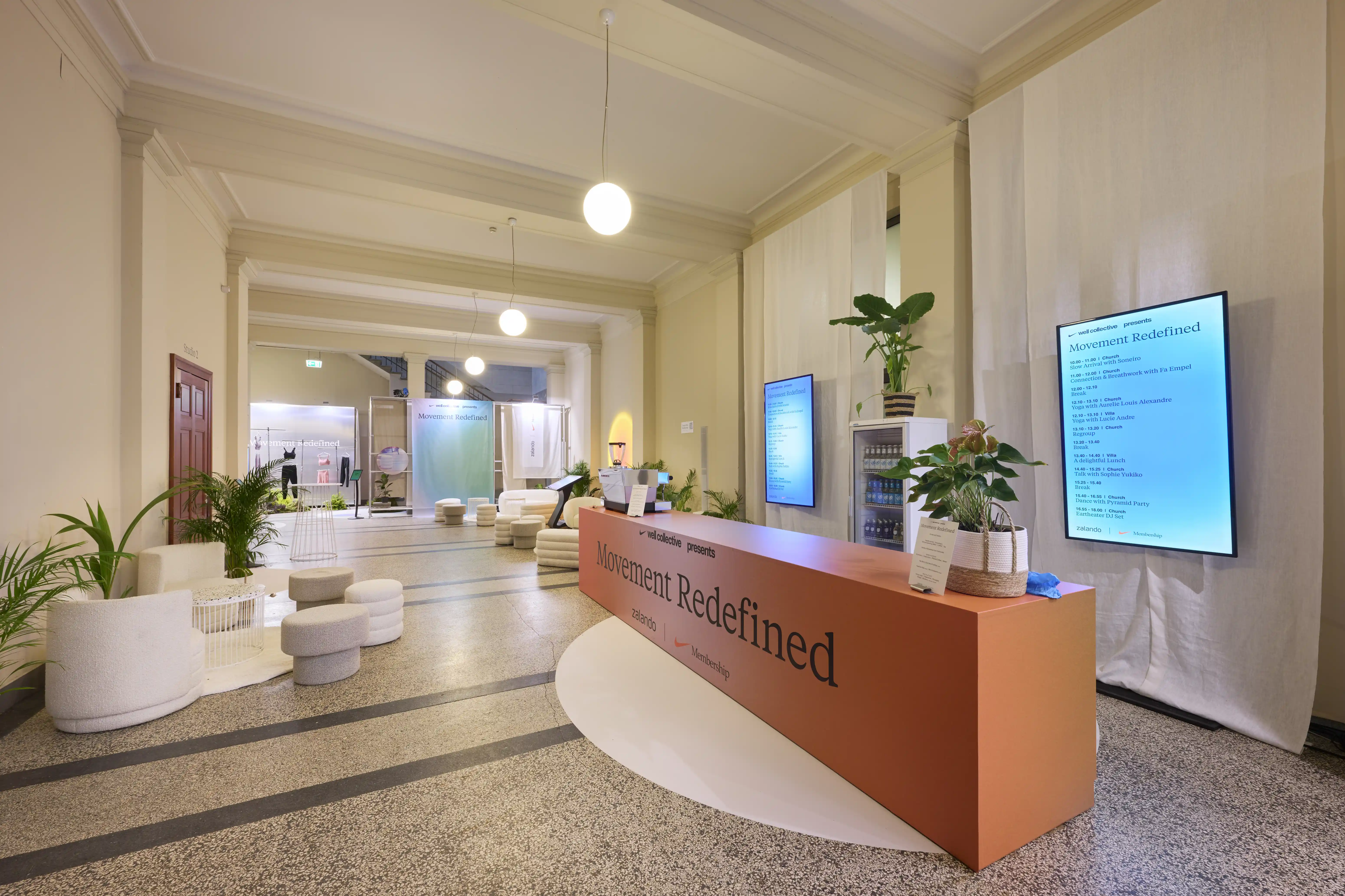 Entrance area with terracotta Movement Redefined counter, white seating pods and programme screen.